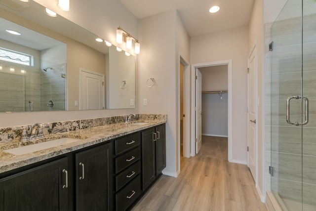 bathroom with hardwood / wood-style floors, vanity, and an enclosed shower