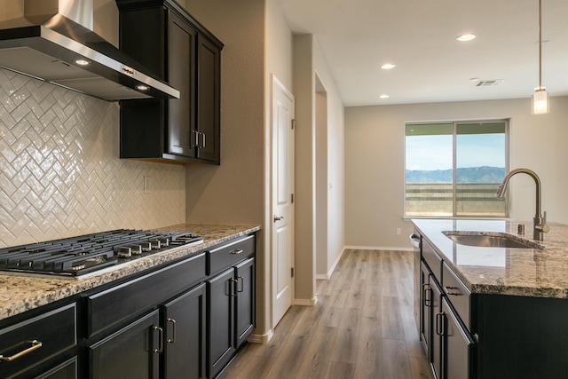 kitchen with a mountain view, wall chimney range hood, sink, light hardwood / wood-style floors, and stainless steel gas cooktop