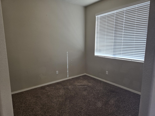 carpeted spare room featuring baseboards