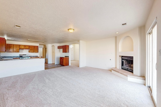 unfurnished living room featuring a fireplace, a textured ceiling, and light colored carpet