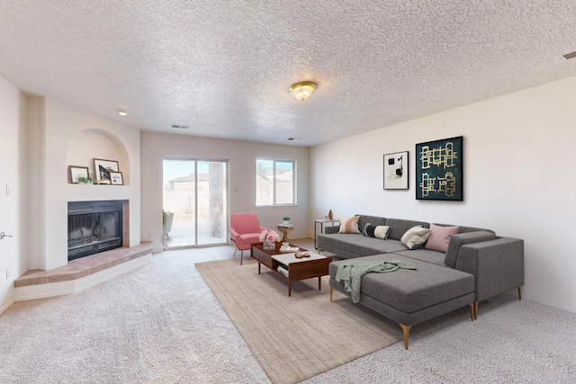 carpeted living room featuring a textured ceiling and a tiled fireplace