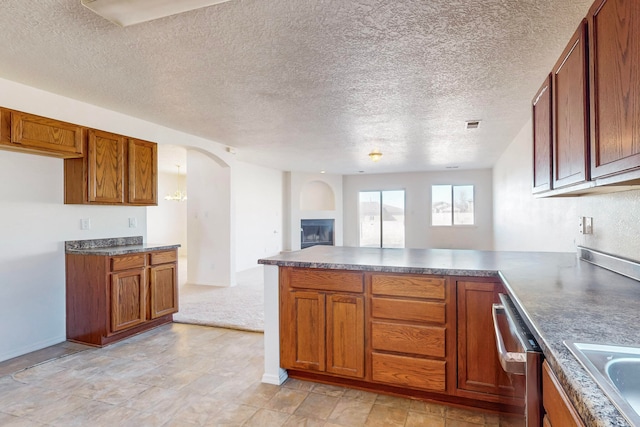 kitchen featuring dishwasher, sink, kitchen peninsula, light colored carpet, and a textured ceiling