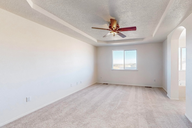 carpeted spare room with a raised ceiling, ceiling fan, and a textured ceiling