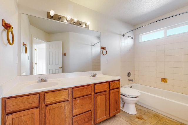 full bathroom with a textured ceiling, vanity, toilet, and tiled shower / bath