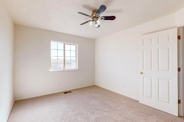 unfurnished room featuring a textured ceiling, light colored carpet, and ceiling fan