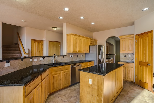 kitchen featuring dark stone countertops, sink, a kitchen island, and stainless steel appliances