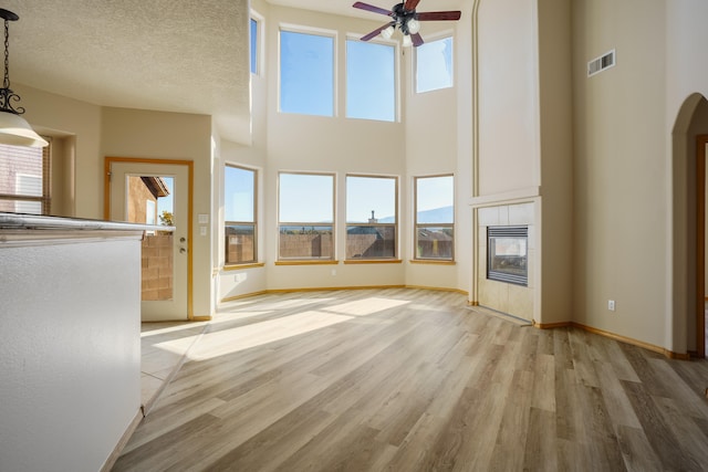 unfurnished living room featuring plenty of natural light, light hardwood / wood-style floors, and a towering ceiling