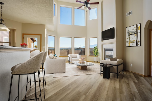 living room featuring a towering ceiling, a textured ceiling, and a wealth of natural light