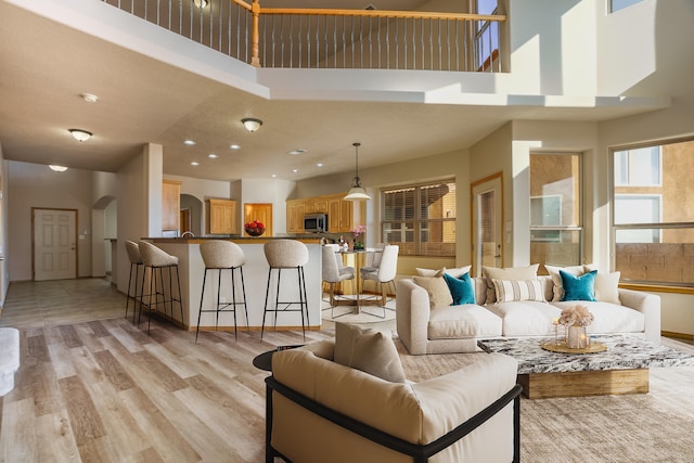 living room featuring a towering ceiling and light wood-type flooring