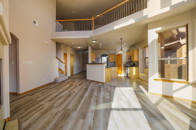 unfurnished living room featuring light hardwood / wood-style flooring and a high ceiling