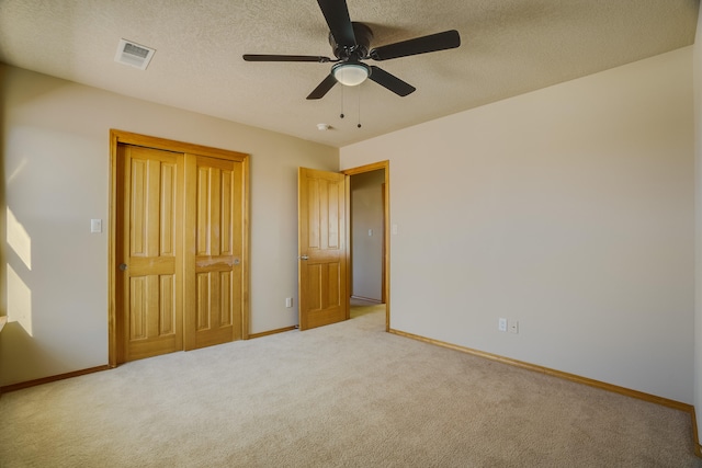 unfurnished bedroom featuring a textured ceiling, ceiling fan, light carpet, and a closet