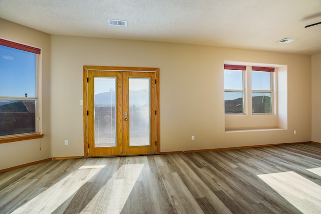 interior space with french doors, light hardwood / wood-style floors, and a textured ceiling