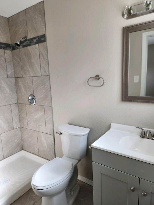 bathroom with vanity, toilet, and a tile shower