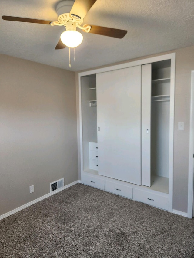 unfurnished bedroom featuring carpet, ceiling fan, a textured ceiling, and a closet