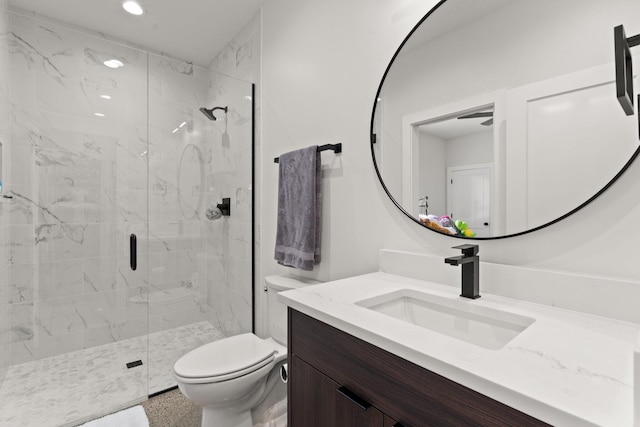 bathroom featuring vanity, a shower with shower door, and toilet