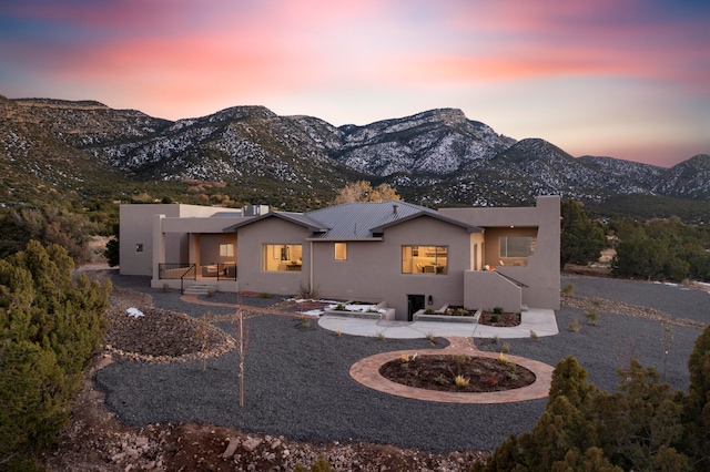 back house at dusk with a patio area and a mountain view