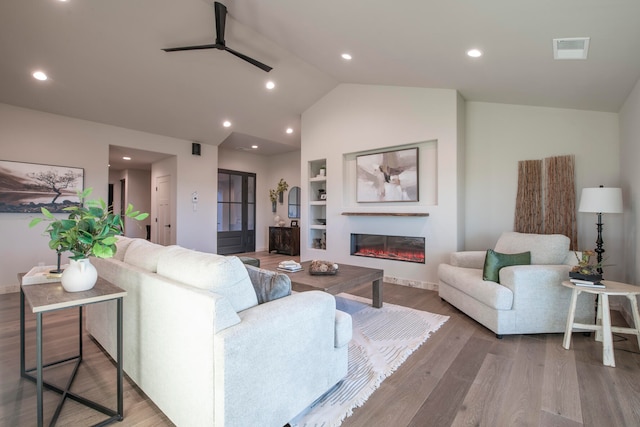 living room featuring ceiling fan, built in features, wood-type flooring, and lofted ceiling