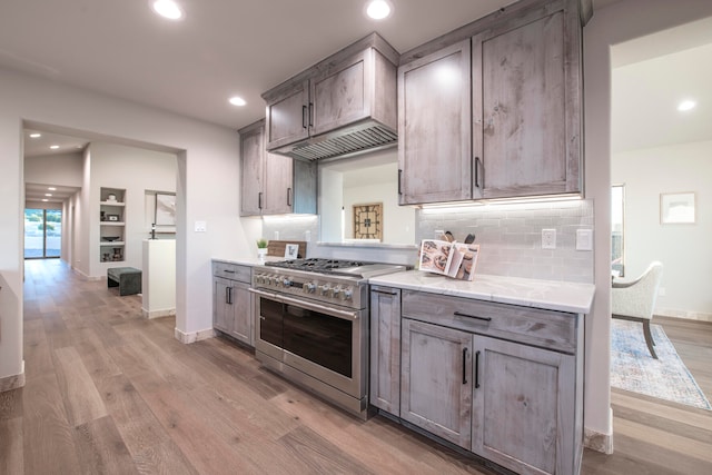 kitchen featuring double oven range, tasteful backsplash, and light hardwood / wood-style flooring