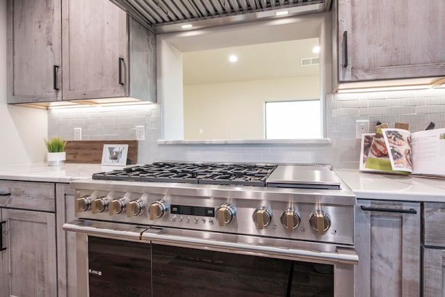 kitchen with high end range, tasteful backsplash, and light stone countertops