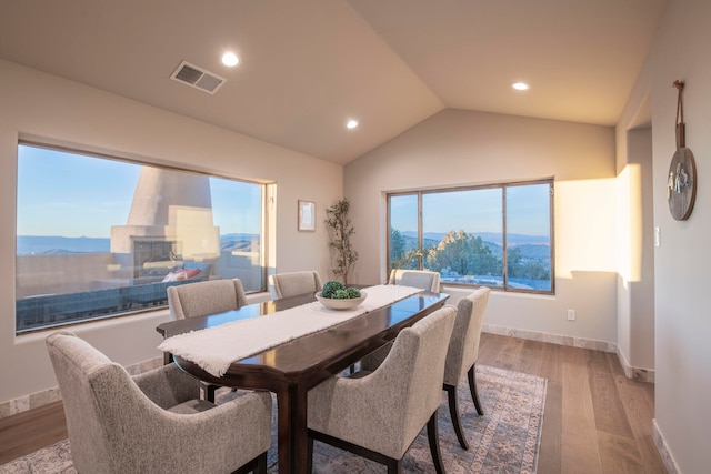 dining room featuring a mountain view, light wood-type flooring, and vaulted ceiling