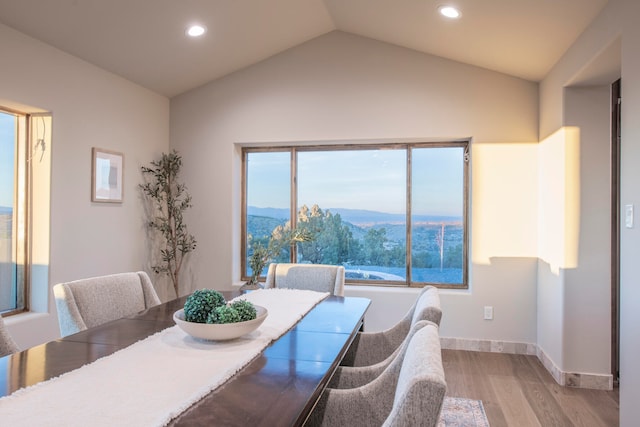 dining space featuring a mountain view, light wood-type flooring, and vaulted ceiling