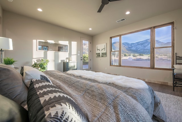 bedroom featuring access to outside, a mountain view, hardwood / wood-style floors, and ceiling fan