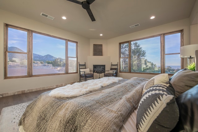 bedroom with hardwood / wood-style flooring, ceiling fan, and a mountain view