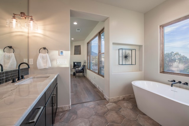 bathroom featuring plenty of natural light, vanity, wood-type flooring, and a washtub