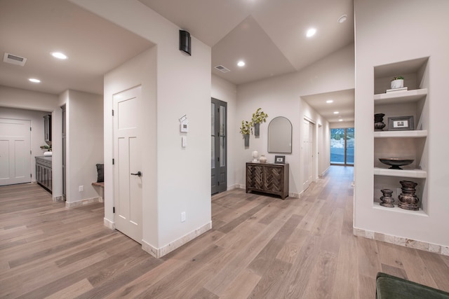 corridor featuring lofted ceiling and light hardwood / wood-style flooring