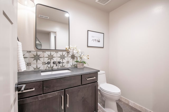 bathroom with vanity, toilet, and tasteful backsplash