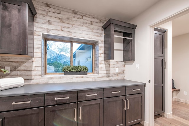 kitchen featuring decorative backsplash, dark brown cabinetry, and light hardwood / wood-style flooring