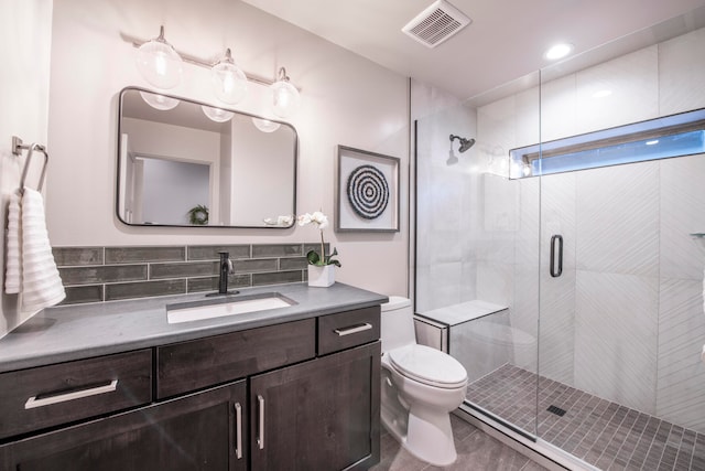 bathroom featuring vanity, toilet, walk in shower, and backsplash