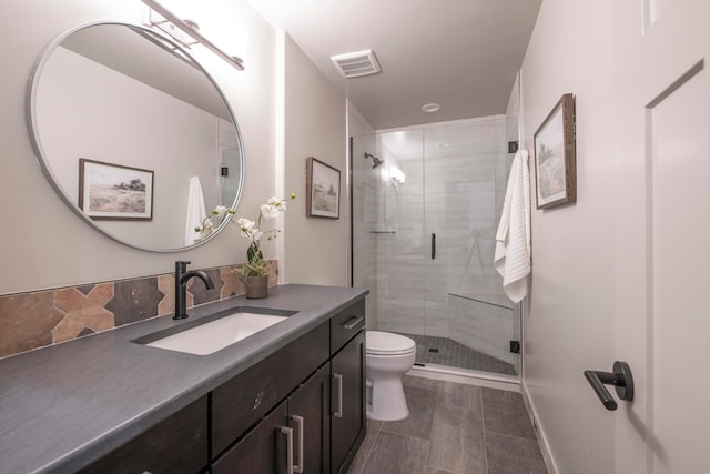 bathroom featuring vanity, toilet, and a shower with shower door