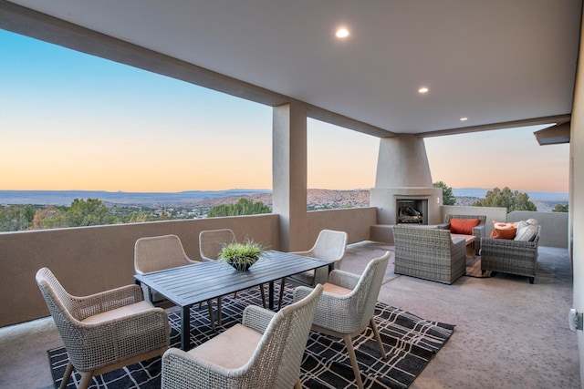 patio terrace at dusk with an outdoor living space with a fireplace