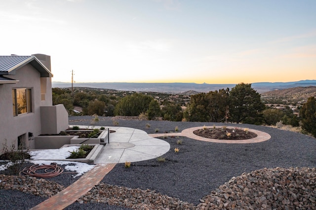 yard at dusk featuring a mountain view and a patio area