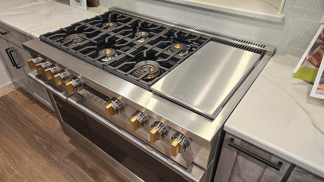 details with wood-type flooring, tasteful backsplash, and high end stainless steel range oven