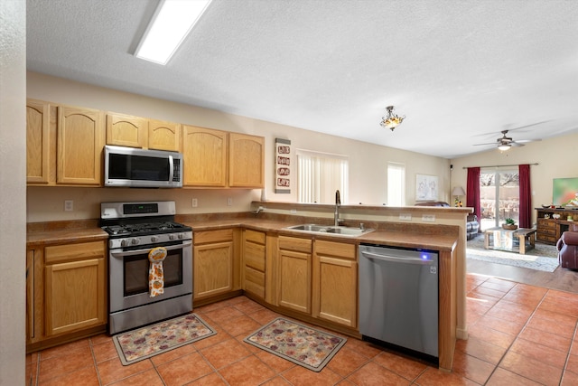 kitchen featuring kitchen peninsula, stainless steel appliances, sink, lofted ceiling, and light tile patterned flooring