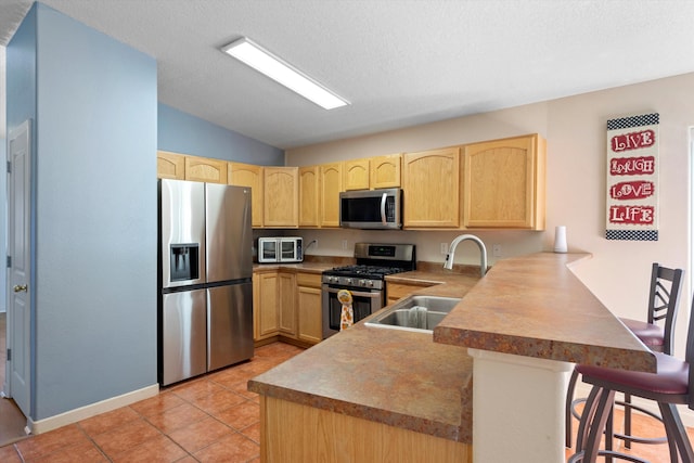 kitchen with kitchen peninsula, light brown cabinetry, stainless steel appliances, and sink