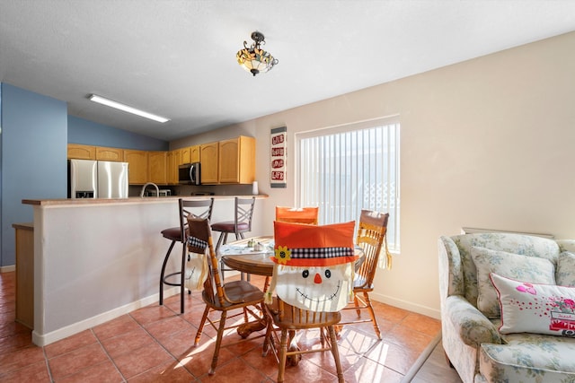 dining area featuring light tile patterned floors and vaulted ceiling