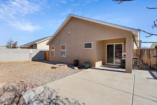 rear view of property with a fire pit and a patio area