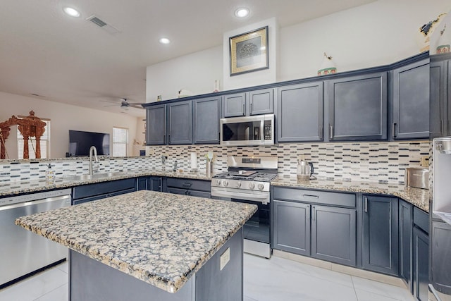 kitchen featuring a center island, light stone countertops, backsplash, and appliances with stainless steel finishes