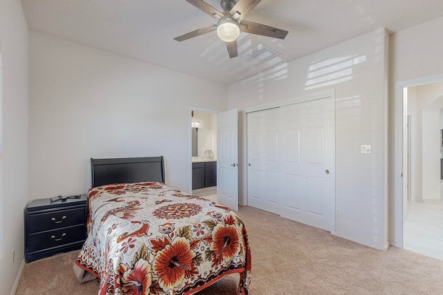 carpeted bedroom with ceiling fan, ensuite bathroom, and a closet