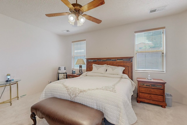 carpeted bedroom featuring ceiling fan and a textured ceiling