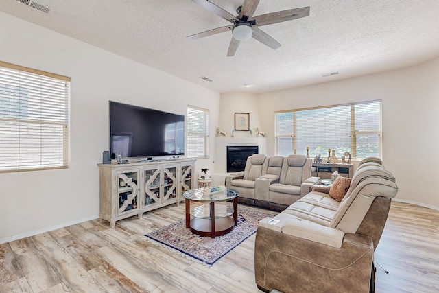 living room with ceiling fan, a textured ceiling, and light hardwood / wood-style flooring