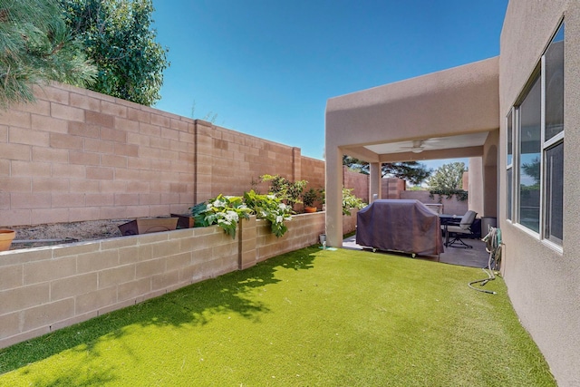 view of yard featuring ceiling fan and a patio