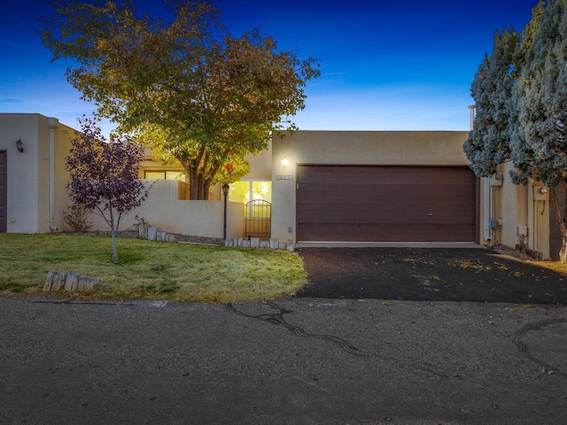 pueblo revival-style home featuring a yard and a garage