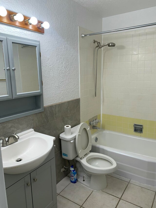 full bathroom featuring tile patterned floors, tile walls, tiled shower / bath combo, and toilet