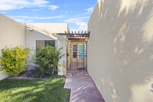 property entrance with a pergola and a lawn