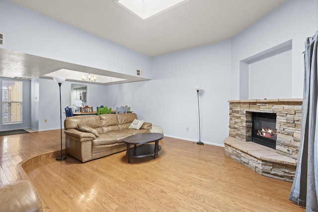 living room with light hardwood / wood-style flooring and a stone fireplace