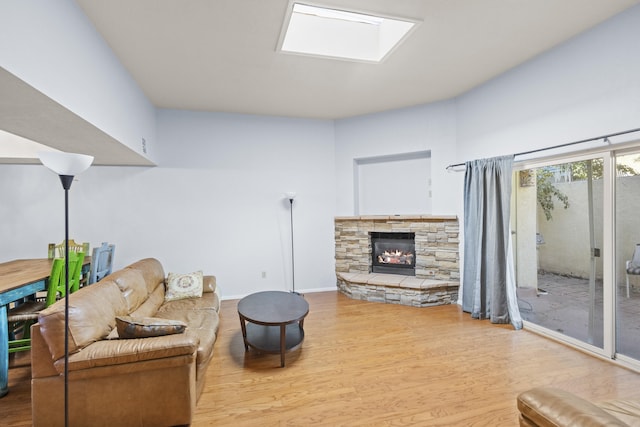 living room with light wood-type flooring and a stone fireplace